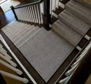 Kaleen wool stair runner with a contrasting chevron pattern and wide speckled stripe, hand-loomed in India from 100% natural wool, styled on a wooden staircase
