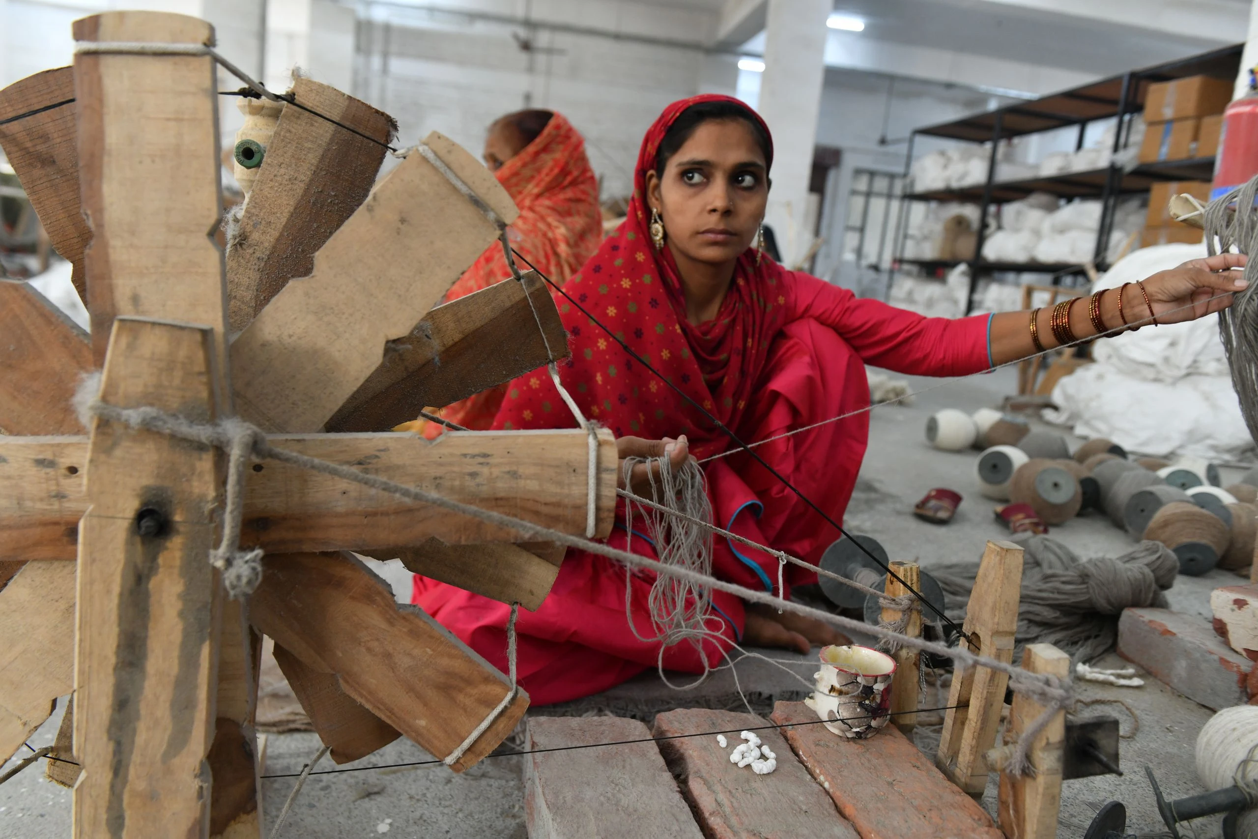 Image of an Indian artisan hand spinning high quality wool yarn on wooden spools in Kaleen’s facility