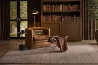 Leather swivel chair beside a bookshelf on a Rhodera rug from Luxe by Kaleen