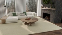 Living room with a cream sectional, round wooden coffee table, and holiday greenery on a cream Affirmed in Beige rug beside a stone fireplace