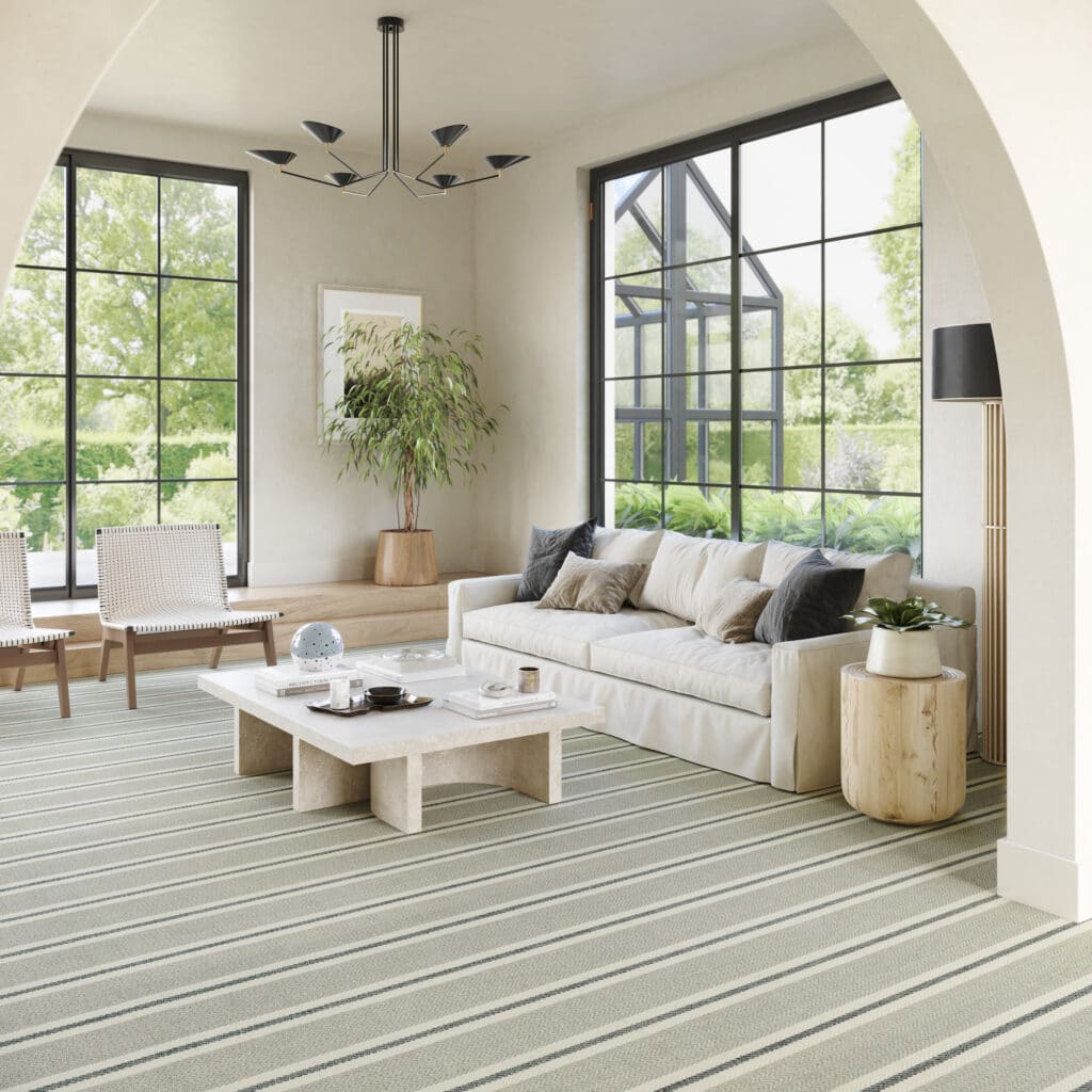 Woven 100% wool broadloom from the Kaleen Savannah Bay Collection, featuring a subtle chevron and contrasting stripe, installed in a large, bright, neutral-toned living room.