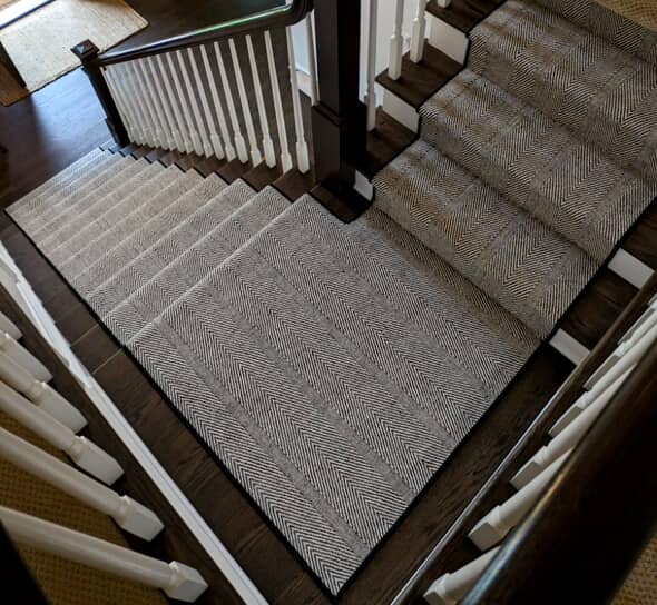 Kaleen wool stair runner with a contrasting chevron pattern and wide speckled stripe, hand-loomed in India from 100% natural wool, styled on a wooden staircase